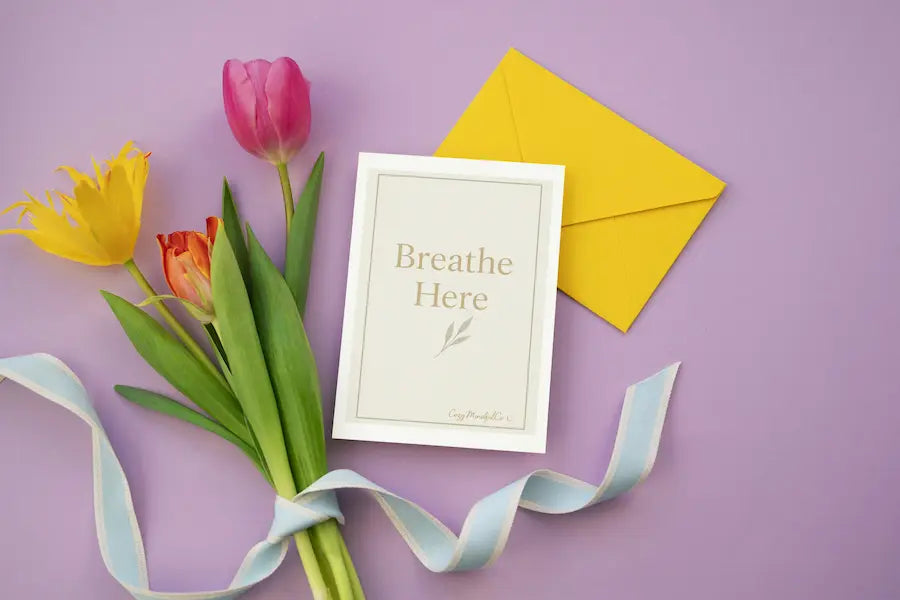Bouquet of tulips with a card with Breathe Here wrote on card and envelope on a purple background