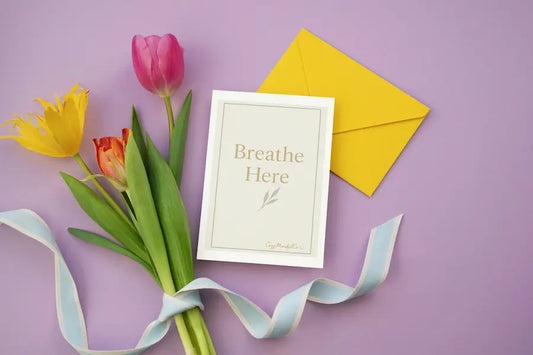 Bouquet of tulips with a card with Breathe Here wrote on card and envelope on a purple background
