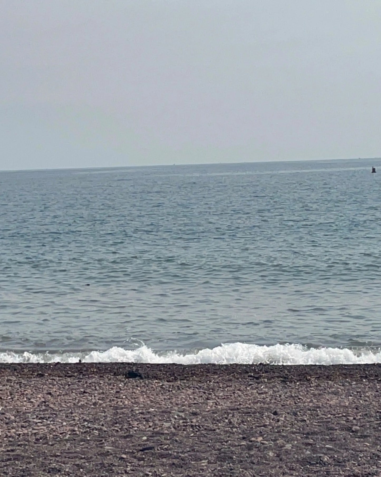 Beach with waves crashing onto the shore and a clear sky.