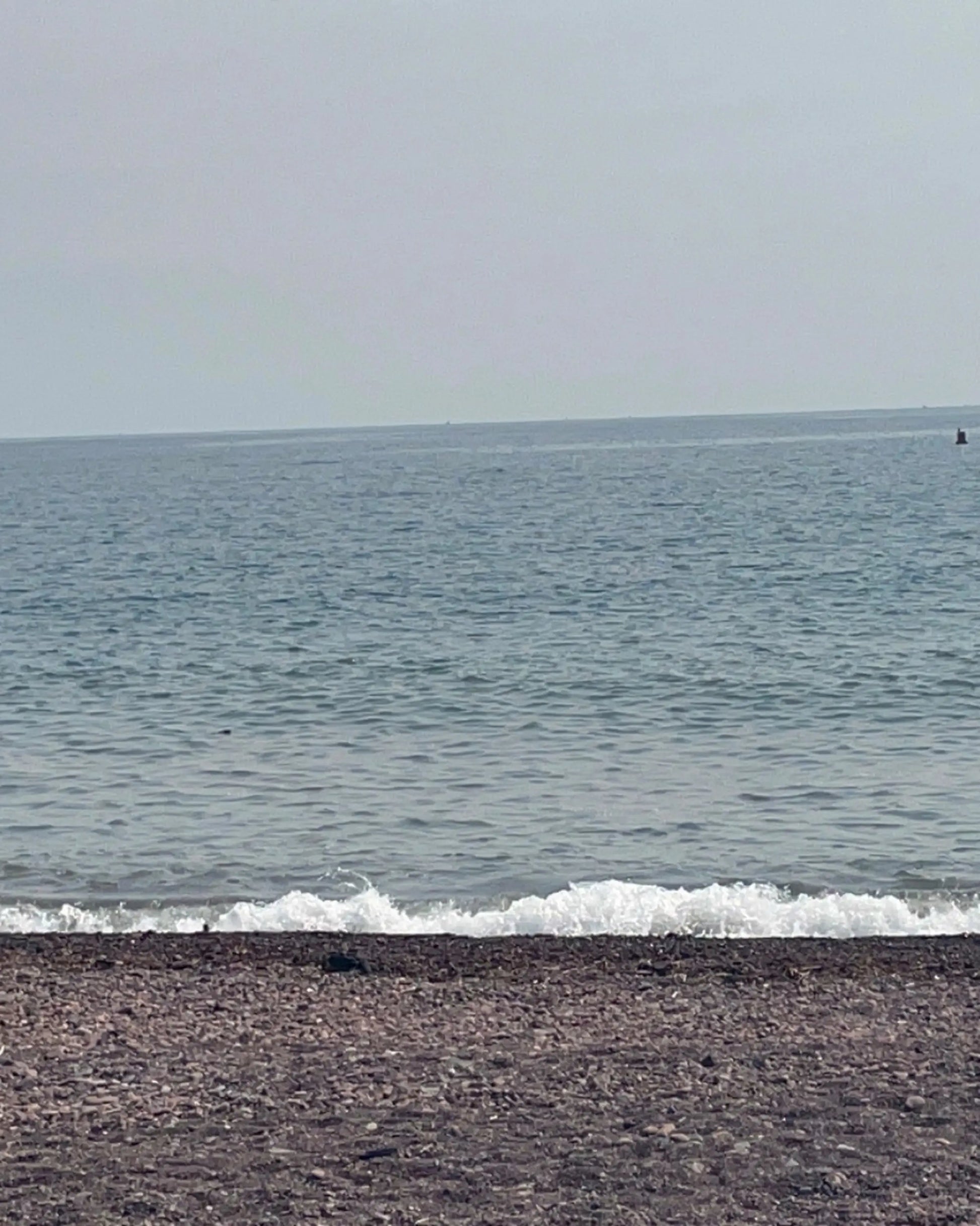 Beach with waves crashing onto the shore and a clear sky.