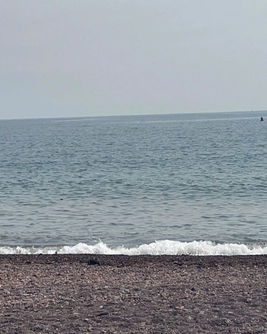Beach with waves crashing onto the shore and a clear sky.